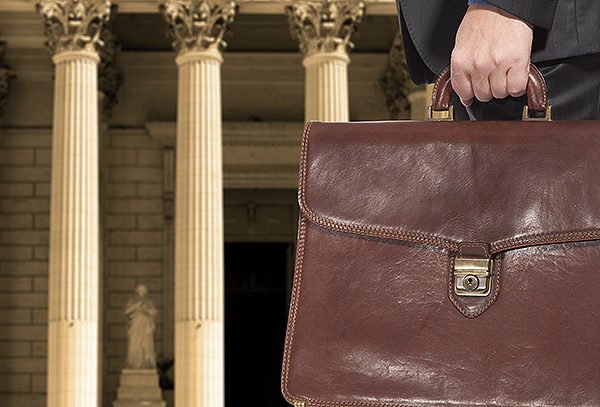 A lawyer with a briefcase on the background of the courthouse